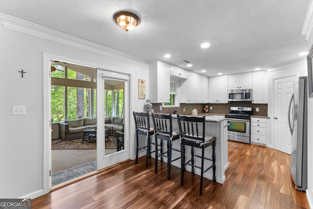 226 Le Paradis Blvd, Sharpsburg, GA 30277 - kitchen with stainless steel appliances, crown molding, a peninsula, white cabinetry, and wood finished floors