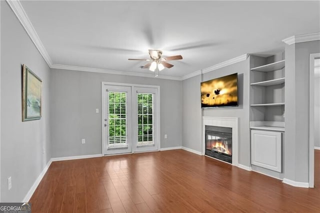unfurnished living room with ceiling fan, a glass covered fireplace, wood finished floors, baseboards, and crown molding