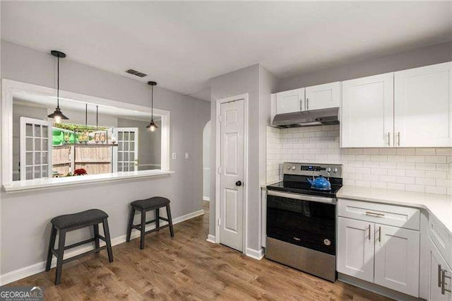 1140 Moorestown Cir, Decatur, GA 30033 - kitchen featuring electric stove, under cabinet range hood, white cabinets, backsplash, and hanging light fixtures