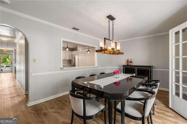 1140 Moorestown Cir, Decatur, GA 30033 - dining space featuring arched walkways, a chandelier, baseboards, light wood-style flooring, and crown molding