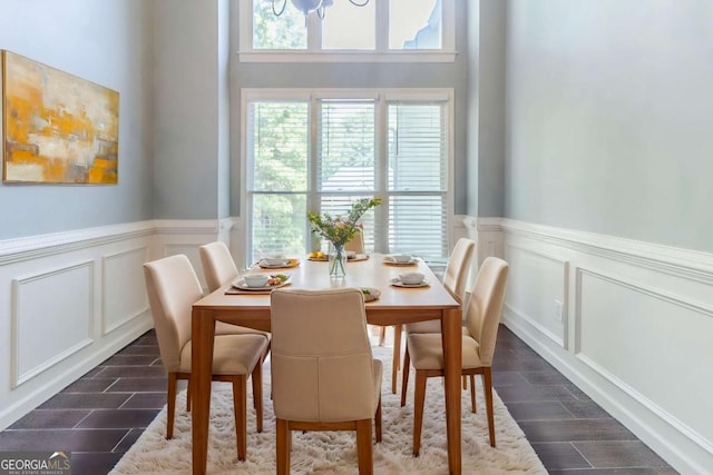 dining room with a decorative wall, a wainscoted wall, wood finish floors, and a chandelier