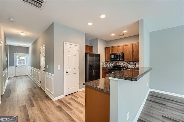 3807 Cyrus Ridge Way, Kennesaw, GA 30152 - kitchen with black appliances, brown cabinets, light wood-style floors, a peninsula, and a wainscoted wall