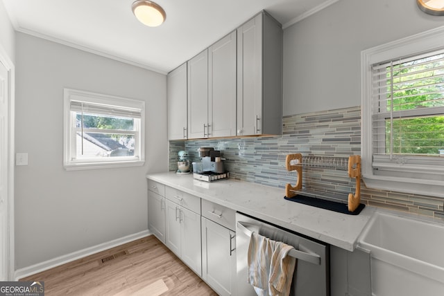 kitchen featuring dishwasher, plenty of natural light, tasteful backsplash, ornamental molding, and light wood finished floors
