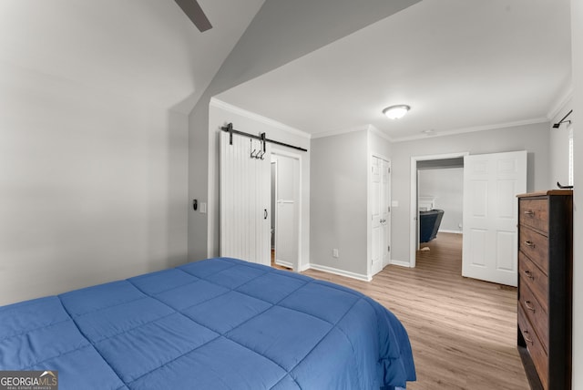bedroom featuring a barn door, wood finished floors, ornamental molding, baseboards, and ceiling fan