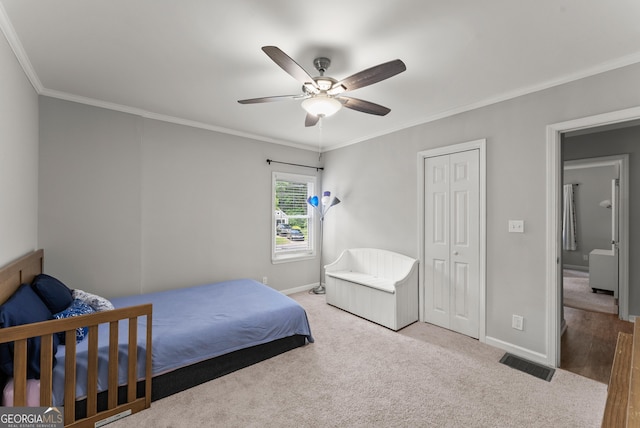carpeted bedroom featuring ornamental molding, baseboards, ceiling fan, and a closet