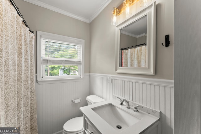 full bathroom featuring toilet, vanity, crown molding, and a wainscoted wall