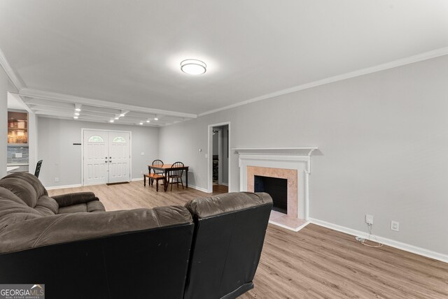living room featuring light wood-type flooring, baseboards, crown molding, and a high end fireplace