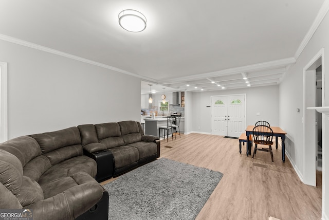 living room with light wood-style floors, ornamental molding, and baseboards