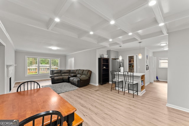 living area featuring coffered ceiling, baseboards, light wood finished floors, beamed ceiling, and a fireplace