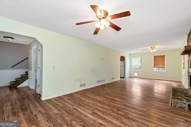 1405 Lumpkin County Pkwy, Dahlonega, GA 30533 - unfurnished living room with a ceiling fan, arched walkways, wood finished floors, stairs, and a stone fireplace