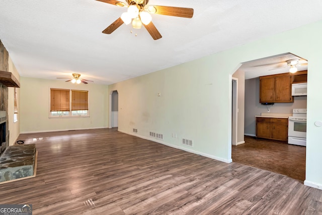 1405 Lumpkin County Pkwy, Dahlonega, GA 30533 - unfurnished living room featuring ceiling fan, arched walkways, dark wood finished floors, a fireplace with raised hearth, and baseboards