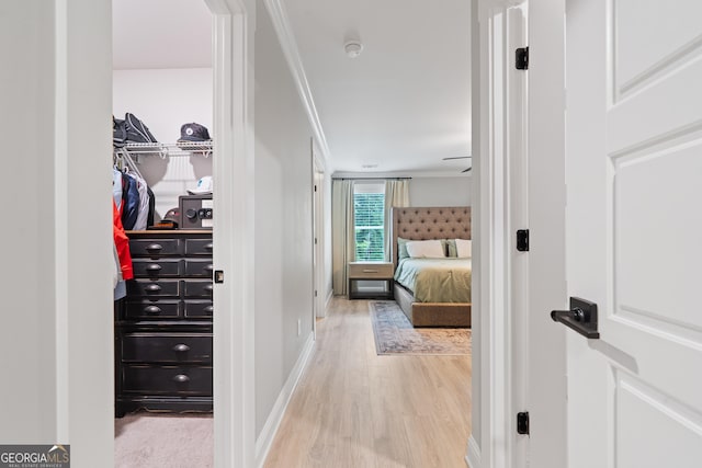 bedroom featuring light wood-type flooring, crown molding, and baseboards