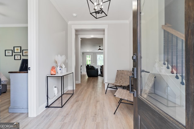 foyer with light wood-style flooring, crown molding, baseboards, a chandelier, and ceiling fan