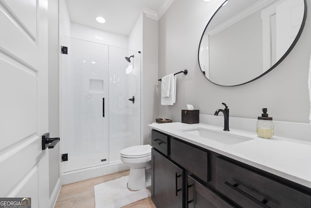 full bath with toilet, a stall shower, wood finished floors, ornamental molding, and vanity
