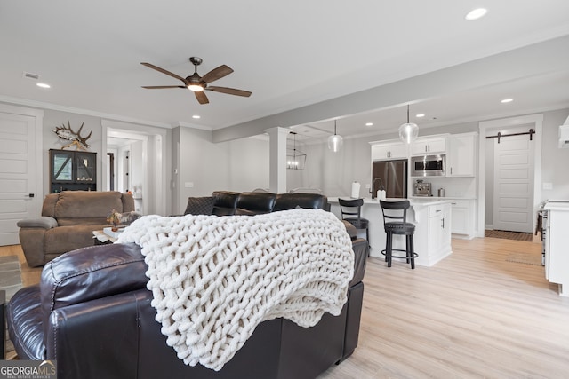living area with ceiling fan, light wood-style floors, recessed lighting, ornamental molding, and decorative columns