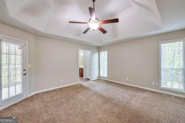 616 Lone Oak Ct, Lithonia, GA 30058 - empty room featuring a tray ceiling, carpet flooring, a ceiling fan, and plenty of natural light