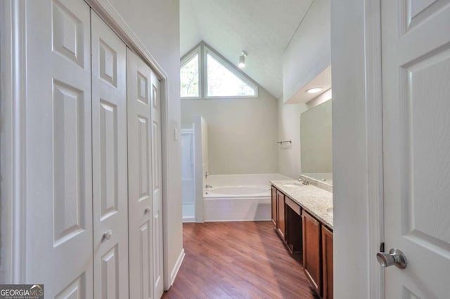616 Lone Oak Ct, Lithonia, GA 30058 - bathroom with lofted ceiling, a bath, a closet, vanity, and wood finished floors