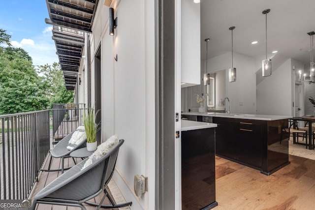 574 Boulevard Pl NE Unit 4, Atlanta, GA 30308 - kitchen with light wood-type flooring, light countertops, a sink, dark cabinets, and hanging light fixtures