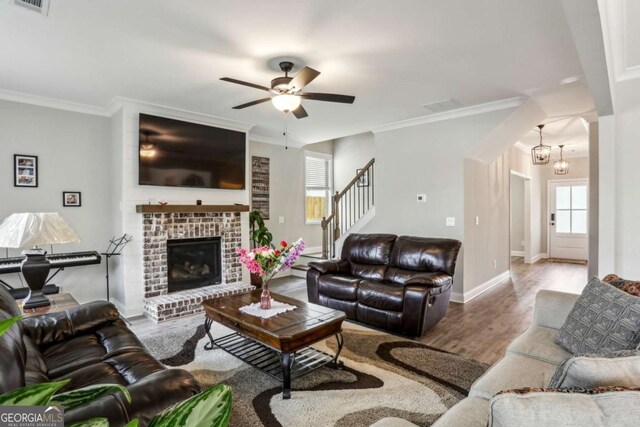 living room featuring wood finished floors, stairway, crown molding, a ceiling fan, and baseboards