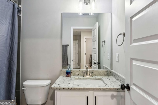 bathroom featuring toilet, vanity, and curtained shower