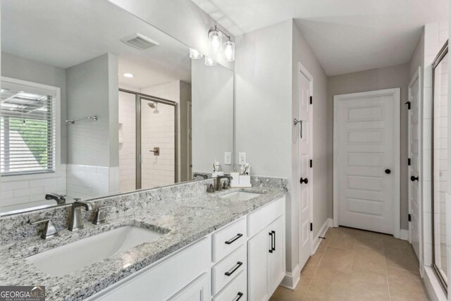 full bathroom with a stall shower, tile patterned floors, double vanity, and baseboards