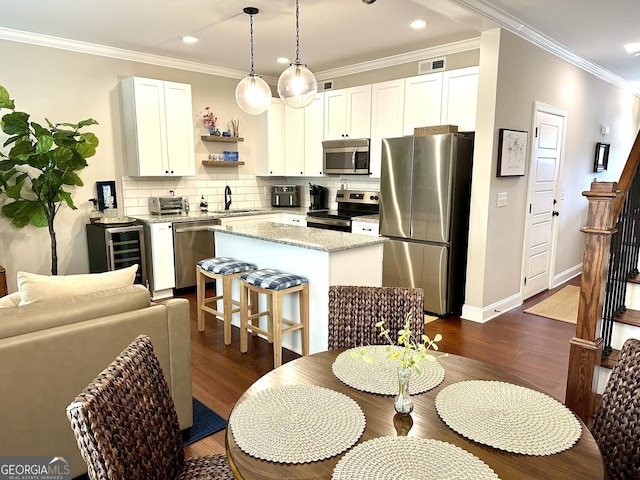 kitchen with appliances with stainless steel finishes, a center island, dark wood-type flooring, a sink, and tasteful backsplash
