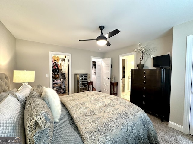 bedroom with a walk in closet, carpet, baseboards, a closet, and ceiling fan