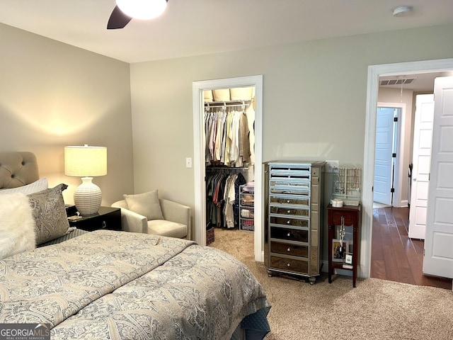 carpeted bedroom with a spacious closet, a closet, wine cooler, and ceiling fan