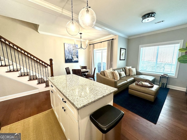 kitchen with a chandelier, dark wood-style flooring, white cabinetry, light stone counters, and hanging light fixtures