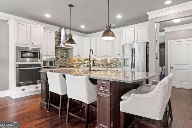 161 Archstone Sq, Mcdonough, GA 30253 - kitchen featuring appliances with stainless steel finishes, wall chimney exhaust hood, ornamental molding, dark wood-type flooring, and a sink