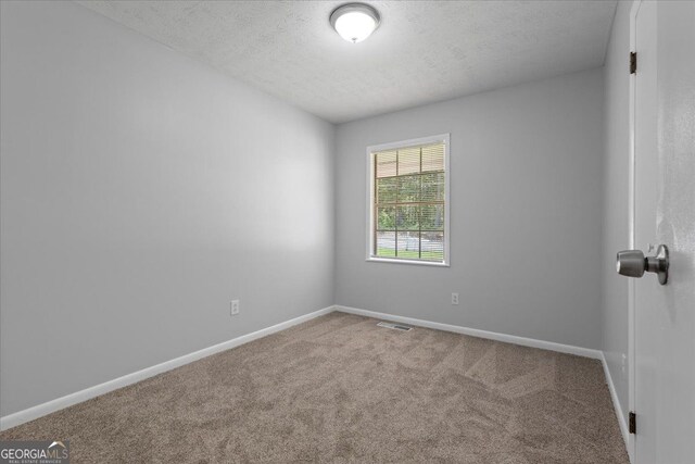 684 Hog Liver Rd, Carrollton, GA 30117 - spare room featuring a textured ceiling, carpet, and baseboards