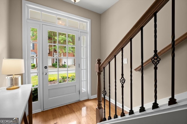 foyer entrance with plenty of natural light, stairs, and light wood finished floors