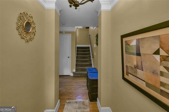 hall featuring crown molding, wood finished floors, stairs, and baseboards