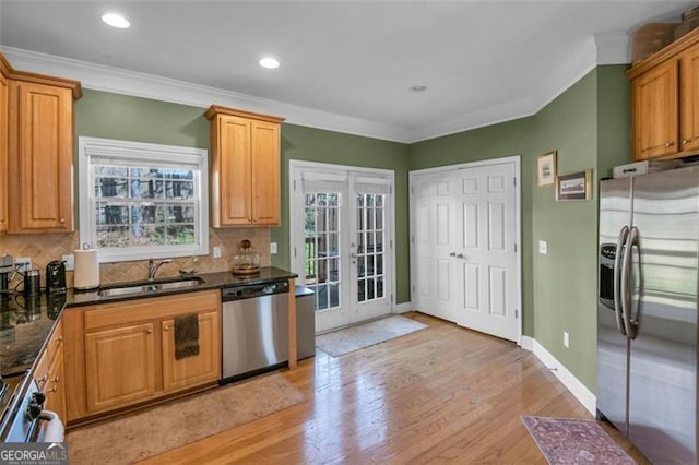 kitchen featuring stainless steel appliances, a sink, ornamental molding, french doors, and decorative backsplash