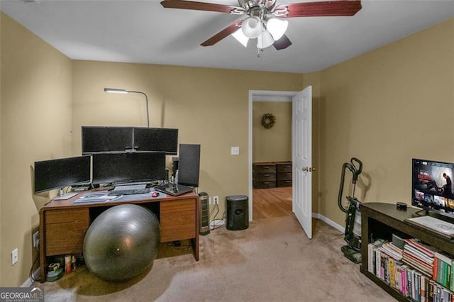 carpeted office space with ceiling fan and baseboards