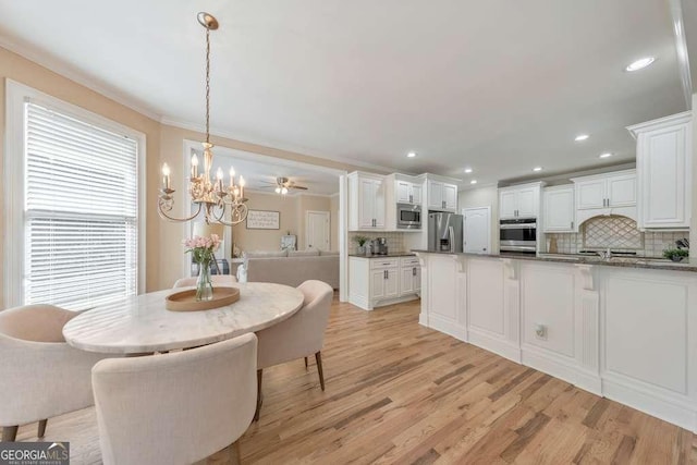 dining area featuring light wood finished floors, a chandelier, ornamental molding, and recessed lighting