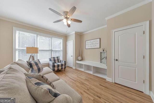 living room featuring light wood finished floors, a ceiling fan, ornamental molding, and baseboards