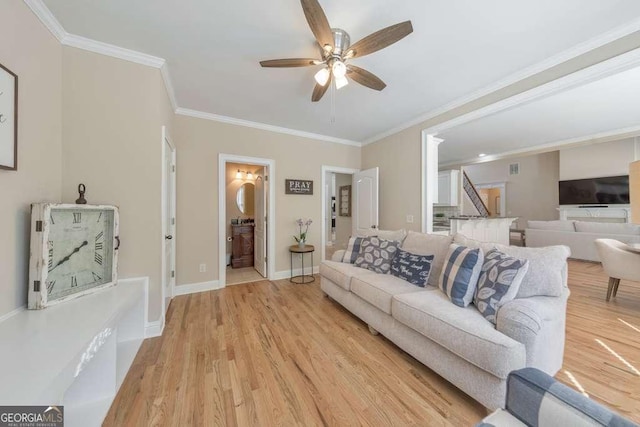 living area featuring ceiling fan, light wood finished floors, ornamental molding, and baseboards