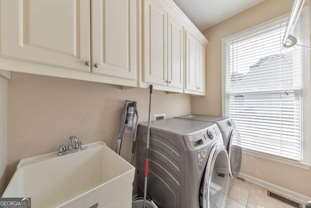 clothes washing area with cabinet space, independent washer and dryer, light tile patterned flooring, and baseboards