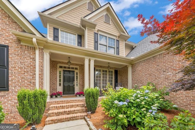 doorway to property with a porch and brick siding