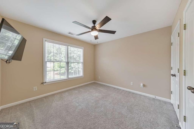 carpeted spare room with a ceiling fan and baseboards