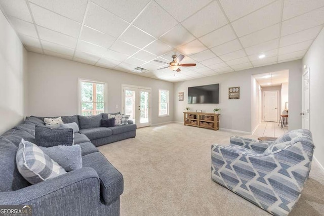 living area featuring carpet flooring, a paneled ceiling, a ceiling fan, and baseboards