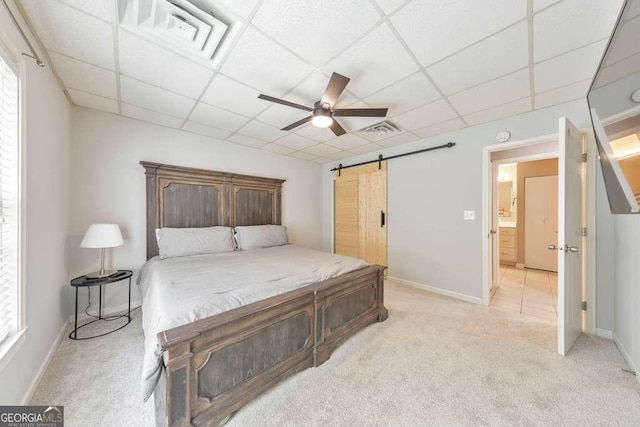 bedroom with a paneled ceiling, a barn door, light carpet, baseboards, and a ceiling fan
