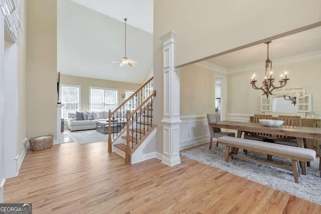 dining room with light wood-style floors, decorative columns, a chandelier, ceiling fan, and stairway