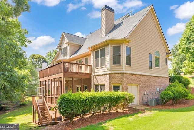 back of property featuring brick siding, a yard, a balcony, and stairs