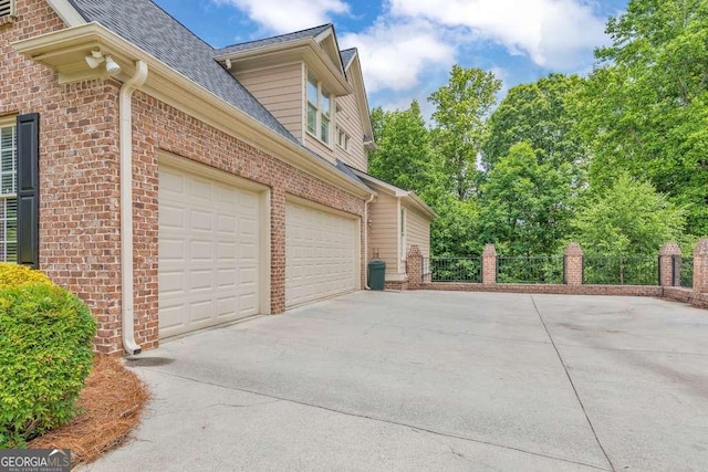garage featuring concrete driveway and fence
