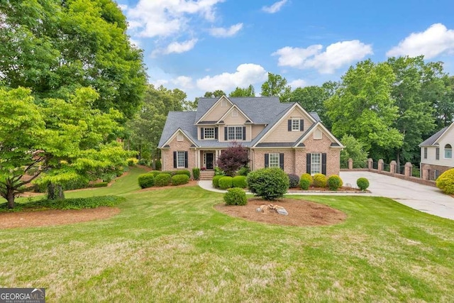 craftsman inspired home with brick siding, a front lawn, and driveway
