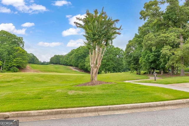 view of community with view of wooded area, a yard, and view of golf course