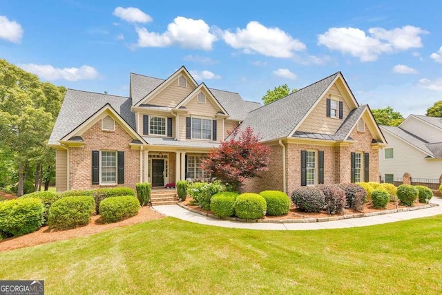 craftsman-style house featuring brick siding, a front yard, and roof with shingles