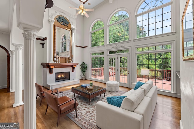 11569 Finley Rd, Johns Creek, GA 30024 - living area with decorative columns, a towering ceiling, crown molding, a warm lit fireplace, and healthy amount of natural light